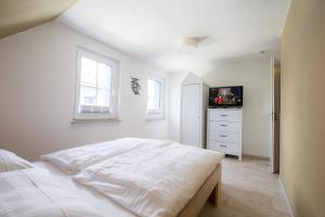 a white bedroom with a bed and a tv at Haus Seemannsgarn in Zingst