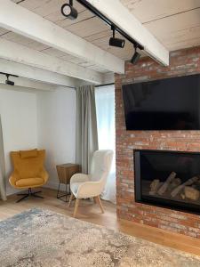 sala de estar con chimenea de ladrillo y TV en Maison ancestrale complètement rénovée 4 chambres, en Bromont