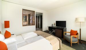 Dormitorio con cama, escritorio y TV en Angel's - das hotel am golfpark, en Sankt Wendel