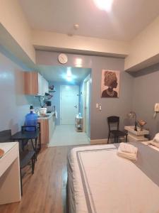 Minimalist Cozy Condo Studio Unit in Grand Residences Cebu في مدينة سيبو: غرفة نوم بسرير ومطبخ مع طاولة
