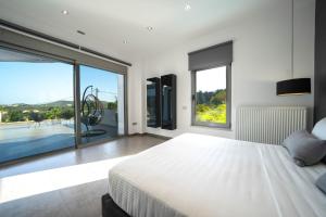 um quarto com uma cama branca e uma grande janela em La Maison Du Soleil em Varípetron