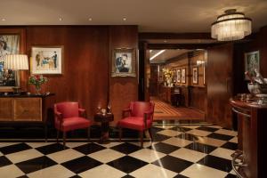 a lobby with red chairs and a checkered floor at The Beaumont Mayfair in London