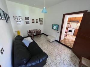 een woonkamer met een zwarte bank en een keuken bij L'altro PAGLIUCO - Casa in Campagna in Sulmona
