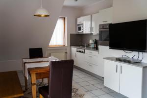 eine Küche mit weißen Schränken und einem Tisch mit einem TV in der Unterkunft Feriendomizil & Weingut Roussel mit Restaurant "La Bonne Adresse" in Bernkastel-Kues
