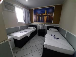 a room with two beds and a picture on the wall at Calamares Hotel São Caetano in São Caetano do Sul