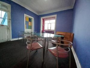 uma sala de jantar com uma mesa de vidro e cadeiras em Casaclub Hostel em Valparaíso