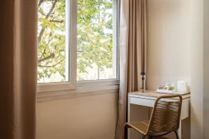een raam in een kamer met een stoel naast een bureau bij BYPILLOW Erba in Girona
