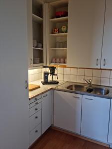eine Küche mit weißen Schränken und einem Waschbecken in der Unterkunft Studio with balcony and a great sea view in Helsinki