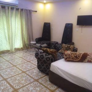 um quarto com uma cama e duas cadeiras e uma televisão em Hotel Versa Appartments lodges Gulberg3 em Lahore