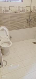 a bathroom with a toilet and a tiled floor at Hotel Versa Appartments lodges Gulberg3 in Lahore