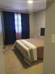 1 dormitorio con 1 cama y una ventana con cortinas azules en Mercado De Propiedades en Córdoba