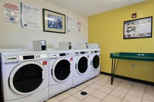 lavadero con 3 lavadoras y una mesa verde en InTown Suites Extended Stay Select Corpus Christi TX, en Corpus Christi
