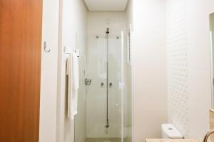 La salle de bains est pourvue d'une douche avec une porte en verre. dans l'établissement Apartamentos Residencial Conte 5 min da Rua Coberta by Achei Gramado, à Gramado