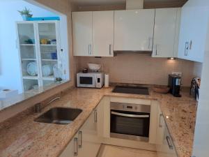 a kitchen with white cabinets and a sink and a microwave at la ventana al mar in Jávea