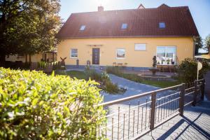 ein gelbes Haus mit einem Zaun davor in der Unterkunft Treppendorfer Apartments in Treppendorf