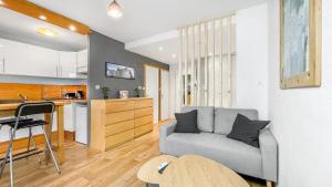 ein Wohnzimmer mit einem Sofa und einer Küche in der Unterkunft HOMEY HARBOR - Proche Tram - Parking gratuit - Balcon privé - Wifi & Netflix in Ambilly