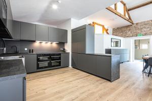 a large kitchen with gray cabinets and a table at Dovedale Manor in Tissington