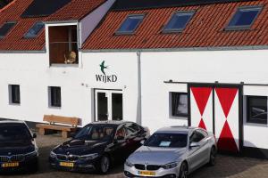 drie auto's geparkeerd voor een wit gebouw bij WijkD in Leende