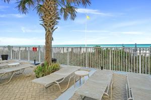 a patio with picnic tables and a palm tree at Emerald Isle by Panhandle Getaways in Panama City Beach