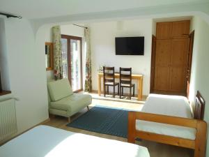 a bedroom with two beds and a chair and a television at Casa Rudi & Ella in Sălişte