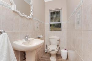 a white bathroom with a sink and a toilet at Coney Glen Cottage in Knysna