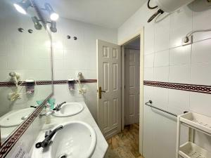 a white bathroom with two sinks and a mirror at Apartamento Caracas in Chiclana de la Frontera