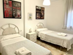 two twin beds in a room with two towels on them at Apartamento Caracas in Chiclana de la Frontera