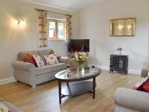 a living room with a couch and a table at Woodlands Dairy Cottage in Billingshurst