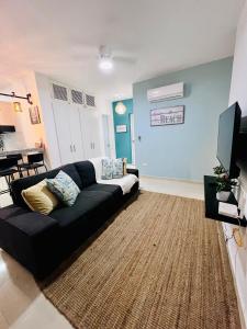 a living room with a black couch and a television at Private Pool View 2BDR in Los Corales Punta Cana in Punta Cana