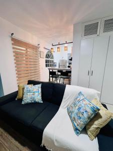 una sala de estar con un sofá negro con almohadas. en Private Pool View 2BDR in Los Corales Punta Cana, en Punta Cana
