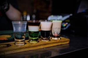 four glasses of different types of drinks on a wooden tray at Кімнати в центрі з усіма зручностями та окремим входом in Ivano-Frankivsk