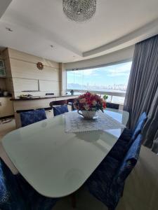 una mesa de comedor blanca con un jarrón de flores. en Luz do Mar Residencial excelente apartamento quadra mar com 3 suítes e uma vista espetácular, en Balneário Camboriú