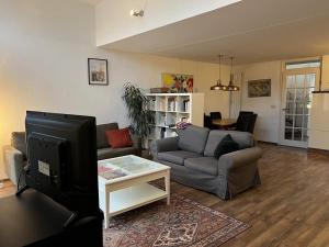 a living room with a couch and a tv at Family house next to train and close to Amsterdam and Schiphol in Almere