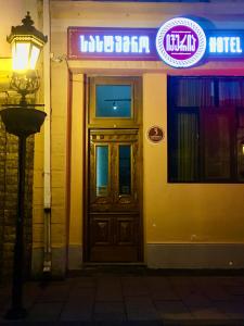 a door to a building with a neon sign at Iveria in Batumi
