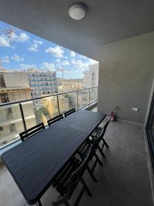een tafel en stoelen op een balkon met een groot raam bij Blue Skies Family Apartment with Terrace in St Paul's Bay