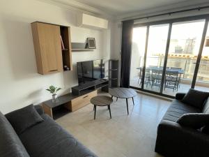 een woonkamer met een bank, een tv en een tafel bij Blue Skies Family Apartment with Terrace in St Paul's Bay