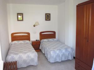 a room with two beds and a dresser in it at Habitaciones López Azcona in Noja
