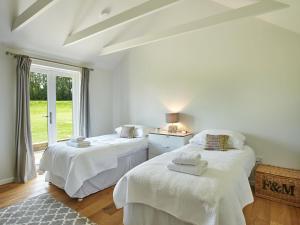 Duas camas num quarto com uma janela em The Stables em Birdham