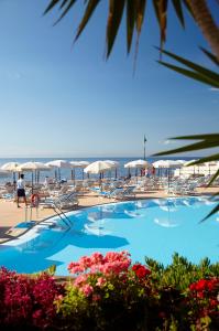 a swimming pool with chairs and umbrellas on the beach at The Cliff Bay - PortoBay in Funchal