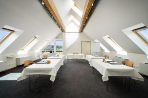 une salle à manger avec des tables blanches et des lucarnes dans l'établissement Angel's - das hotel am fruchtmarkt, à Saint-Wendel