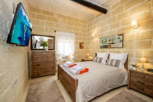 una camera da letto con un letto grande e una TV a schermo piatto di Dar It-Torri Holiday Home a Kerċem