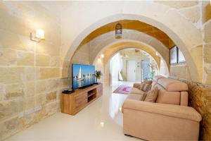 uma sala de estar com um sofá e uma televisão em Dar It-Torri Holiday Home em Kerċem