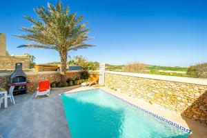 una piscina con 2 sillas y una pared de piedra en Dar It-Torri Holiday Home en Kerċem