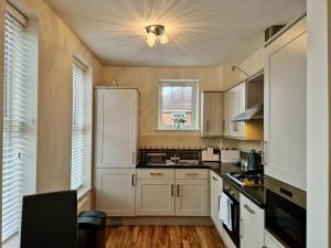 a kitchen with white cabinets and a window at Spacious Luxury Serviced Apartment next to City Centre with Free Parking - Contractors & Relocators in Coventry
