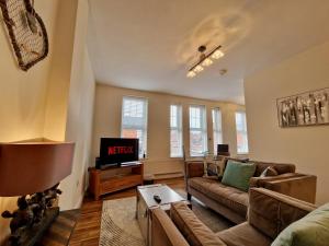 a living room with a couch and a tv at Spacious Luxury Serviced Apartment next to City Centre with Free Parking - Contractors & Relocators in Coventry