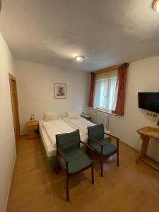 a bedroom with a bed and two chairs and a television at Waldrestaurant VIDA in Kapfenberg