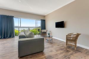 een woonkamer met een bank en een tv bij Coney Glen Views in Knysna
