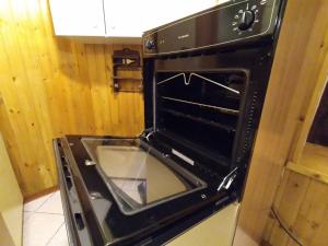 een zwarte oven met de deur open in een keuken bij GRAYNITE-Old Village Apartment in Ponte di Legno