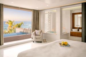 a bedroom with a view of the ocean and a tub at Cap St Georges Villas in Peyia