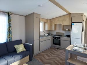 uma sala de estar com um sofá azul e uma cozinha em Hoburne Bashley Self-Catering Holiday Home em New Milton